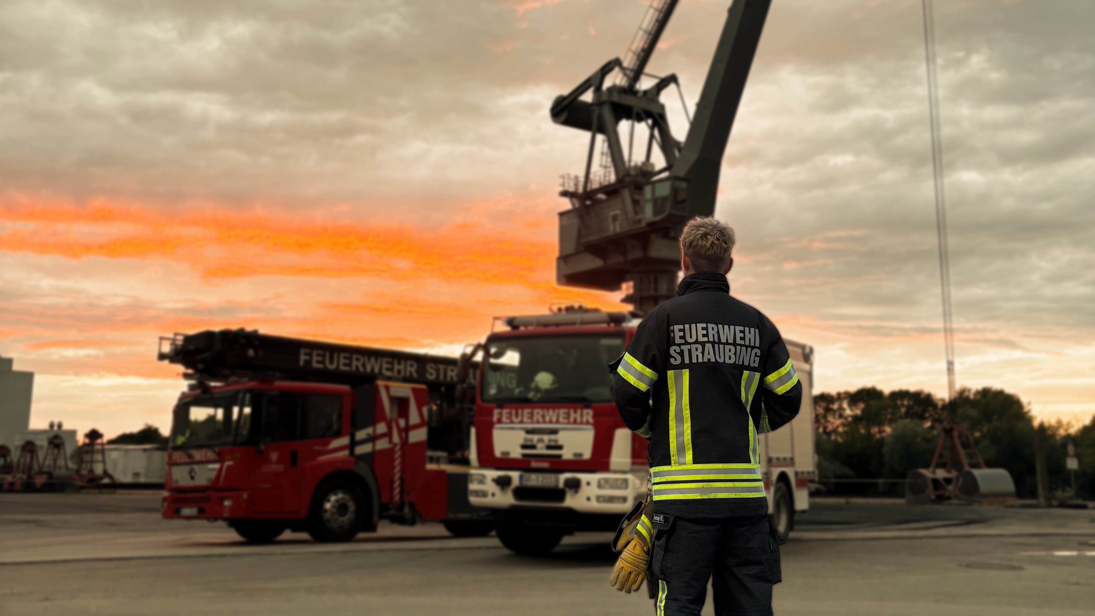 Feuerwehrmann vor mehreren Feuerwehrfahrzeugen